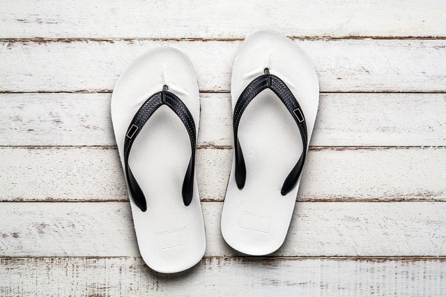 White Beach flip flop on white wooden floor