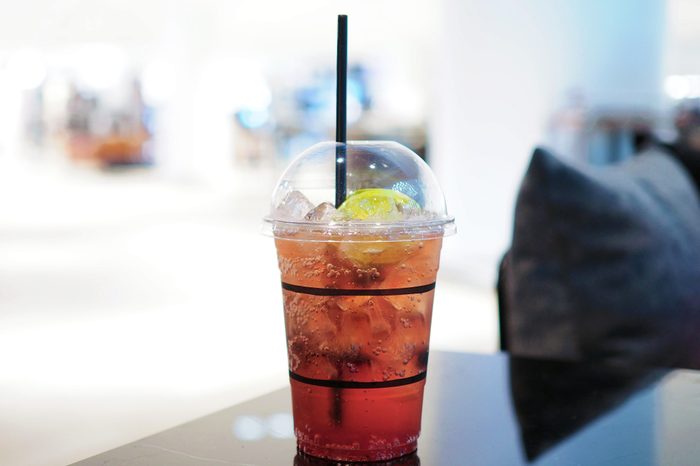 A refreshing plastic glass of iced lemon tea mixed with blueberry on the table. Selective focus.