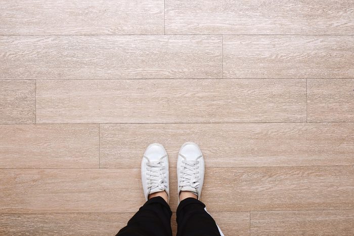 Selfie of feet in fashion sneakers on wooden floor background, top view with copy space