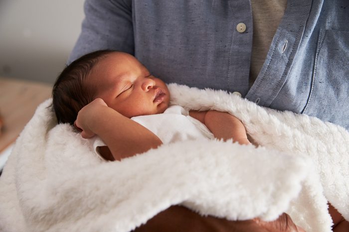 Close Up Of Father Holding Newborn Baby Son In Nursery
