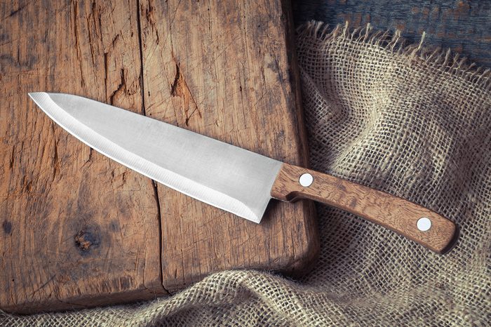 Big kitchen knife lying on an old cutting board