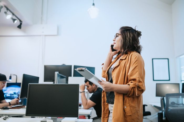 A young entrepreneur at her place of work. She discusses a project she is working on with a client on her smartphone.