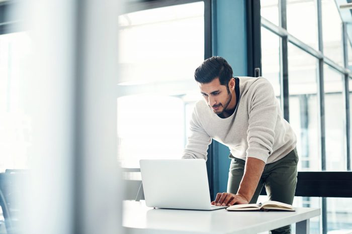Shot of a young businessman using a laptop at his desk in a modern office