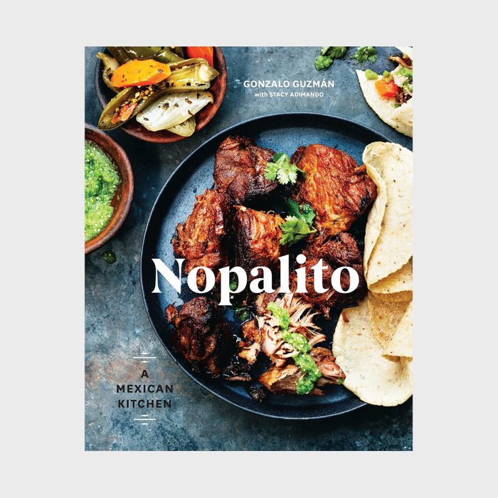 Plate of grilled meat garnished with herbs, tortillas, and salsa; set on a stone surface. Text: 