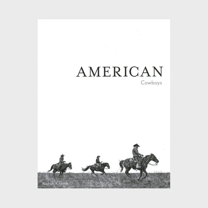 Cowboys ride horses across a grassy field beneath the bold text 