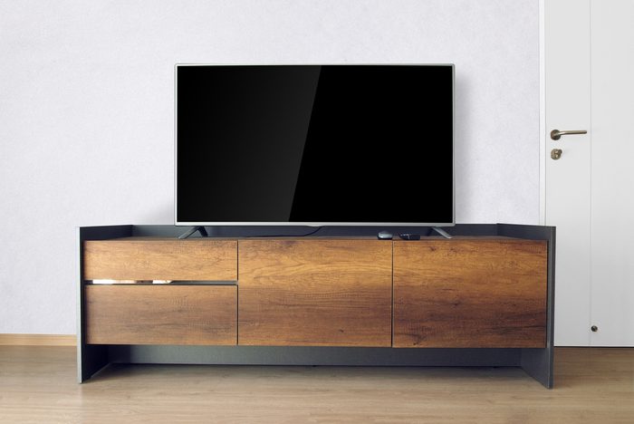 Led TV on TV stand in empty room with white concrete wall. decorate in loft style.