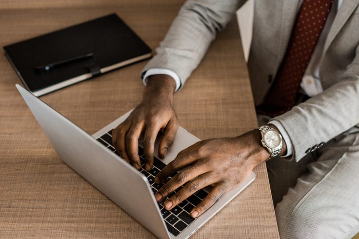 partial view of african american businessman typing on laptop