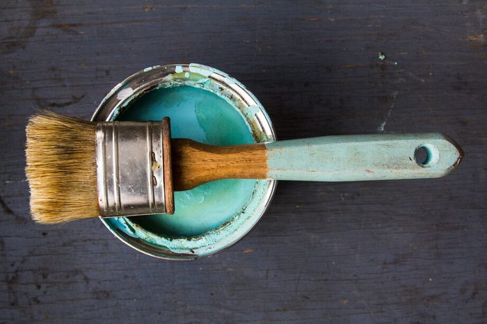 one brush lies on the bank of paint turquoise color on gray wooden background