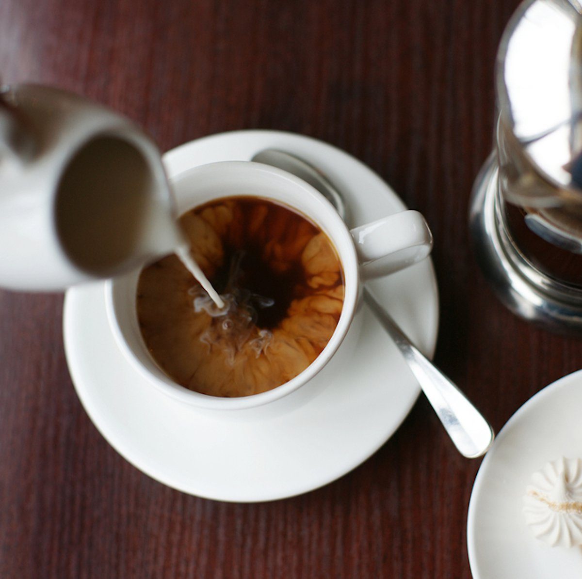 Someone adds milk to black coffee