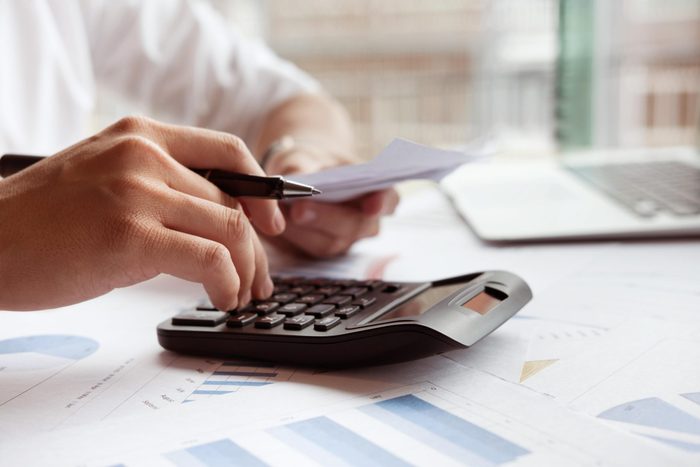 Man calculate domestic bills at home. Businessman using calculator at modern office. Young male checking balance and costs. Start up counting finance. Business people doing paperwork for paying taxes