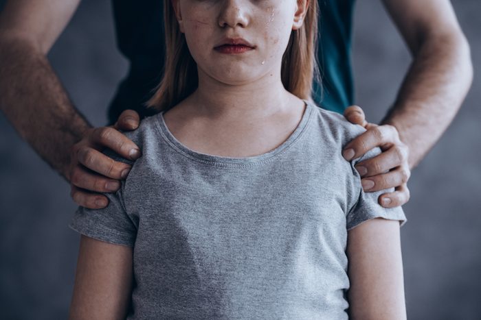 Male hands on little crying girl, concept of children exploitation