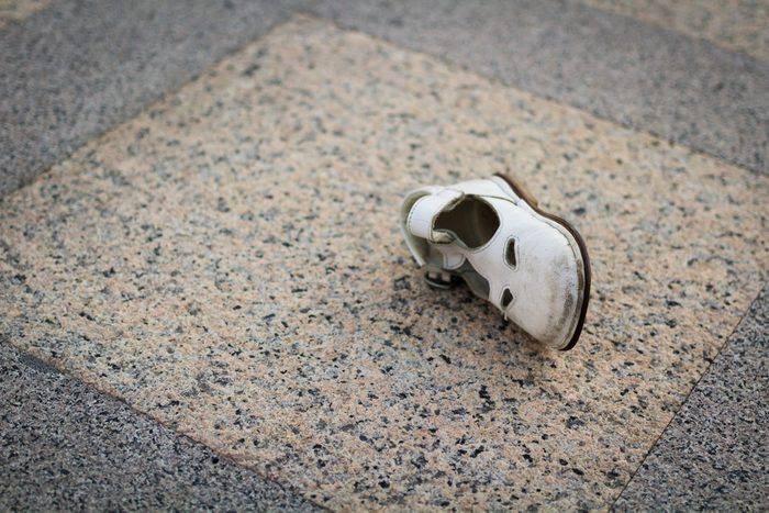 Lost children's shoes. One white sandal girls. Old cute. abandoned on the sidewalk