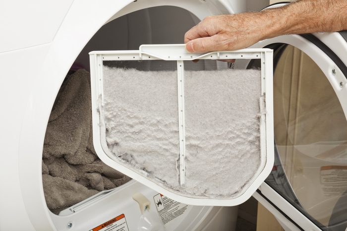 Hand holding a clothes dryer lint filter that is covered with lint.