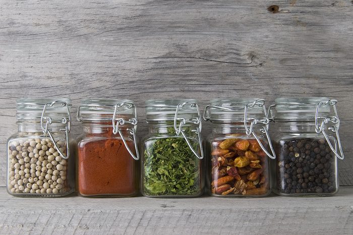 Glass jars with some spices on an old wooden stand.