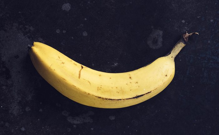 Ripe yellow bananas fruits, bunch of ripe bananas with dark spots on a dark background