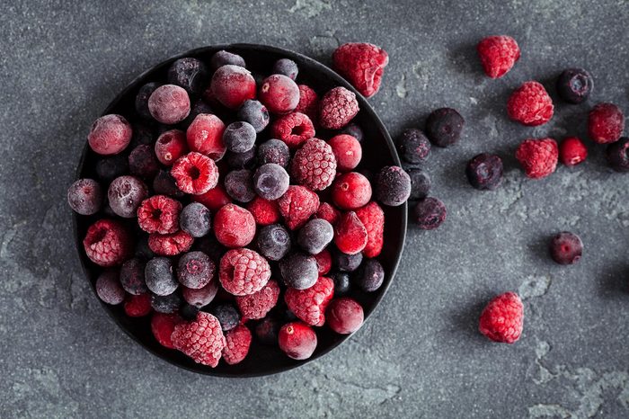 Frozen raspberry, blueberry, cranberry on black background. Frozen fruit. Top view, flat lay, close up.