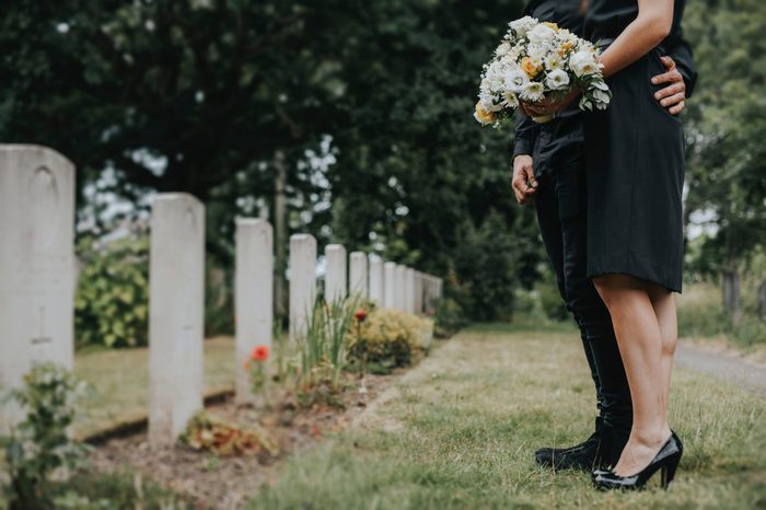 Couple standing together by a gravestone