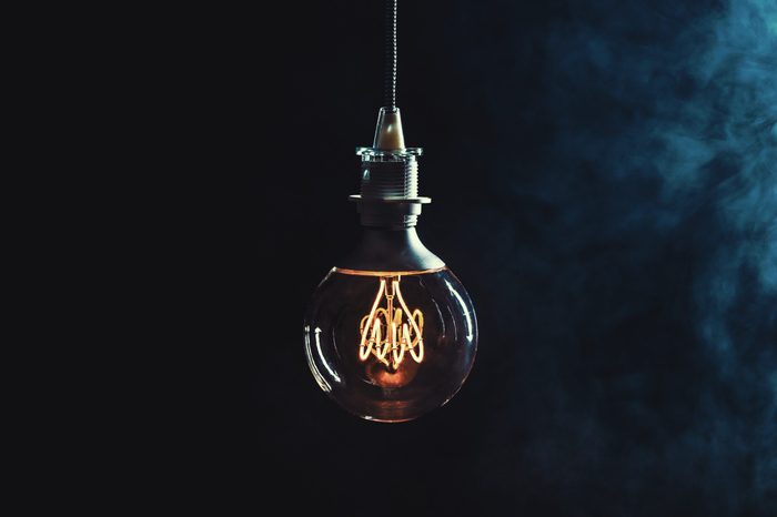 Vintage lightbulb on dark background with bright yellow shining wire