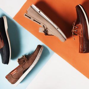 Shoes are scattered and tilted on a two-tone surface of blue and orange, showcasing their different colors and styles.
