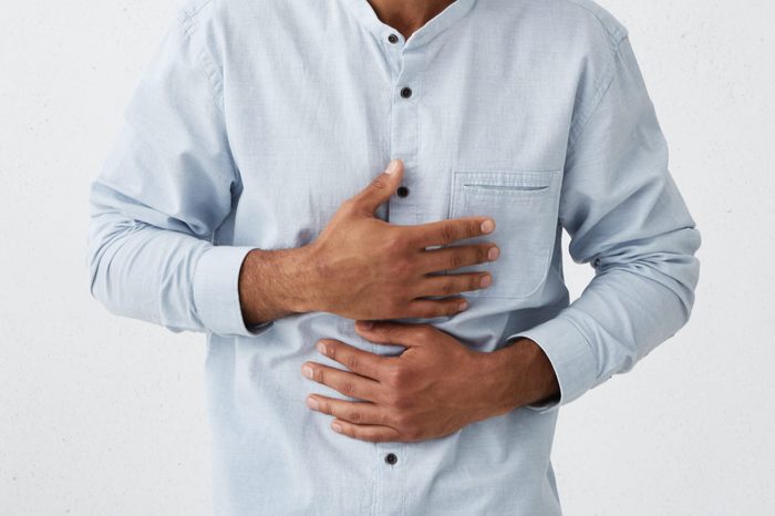 Positive attitude and genuine human emotions. Waist up portrait of cheerful joyful young African man holding hands on stomach while laughing out loud at something funny, not suppressing his feelings