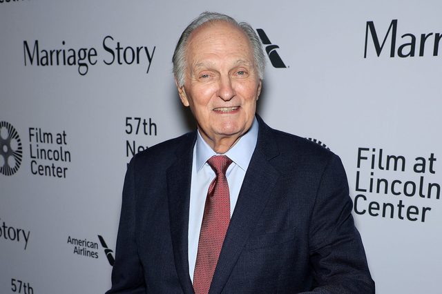 Man smiling, wearing a suit and red tie, standing in front of a backdrop with "Marriage Story" and "Film at Lincoln Center" text.