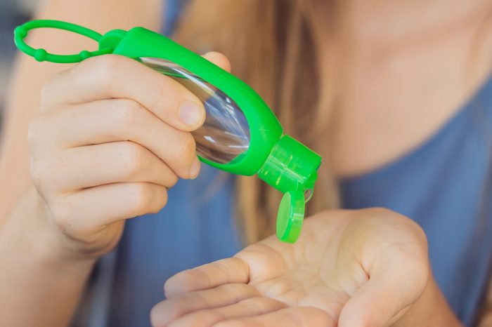 Women's hands using wash hand sanitizer gel pump dispenser. BANNER long format