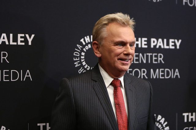 A smiling man stands at an event, wearing a pinstripe suit and red tie. The background features "THE PALEY CENTER FOR MEDIA" text.