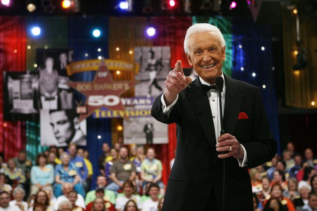 Man gestures and smiles, holding microphone on stage; audience watches. Background displays a star and text: "Bob Barker's 50 years in television."