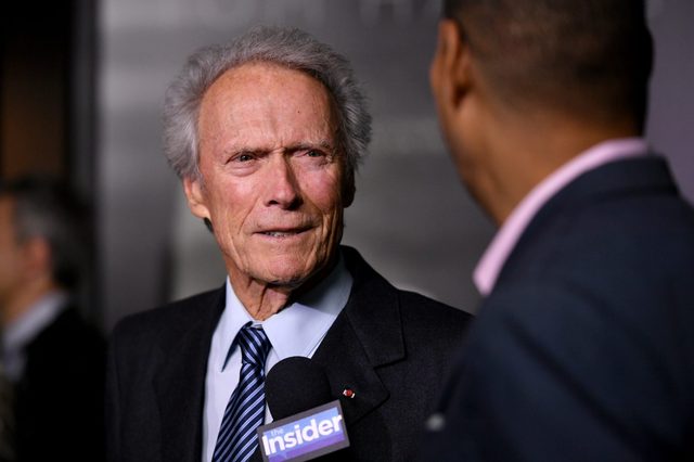 Man speaks into a microphone labeled "the Insider," conversing with another person in a formal setting.