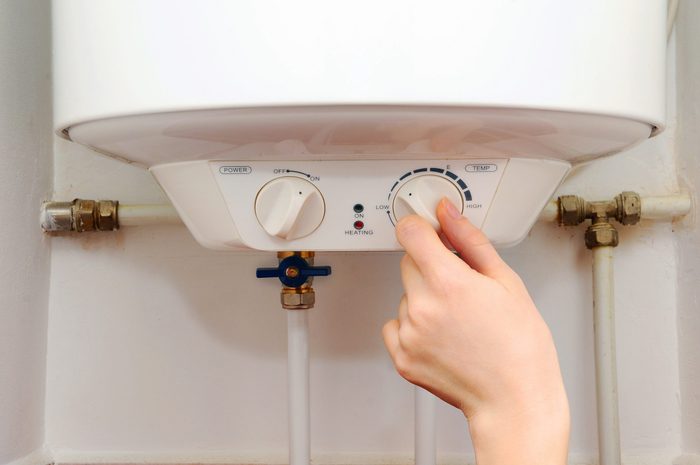 Hands young women set the temperature of the water in the electric boiler.