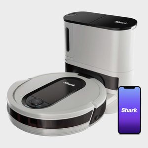 Robot vacuum lies beside charging dock and smartphone displaying 