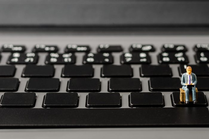 miniature figure business man sitting on computer laptop keyboard