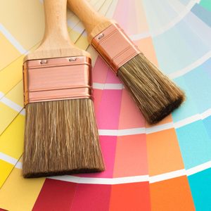 Brushes resting on a vibrant color swatch palette showing a spectrum of colors from yellow to blue, suggesting painting or design planning.
