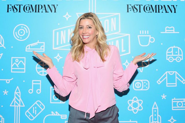 Person smiling, stands with arms outstretched; background features "Fast Company" logos and various white icons on a blue backdrop.