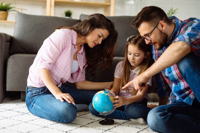 Parents and daughter looking at globe in living room