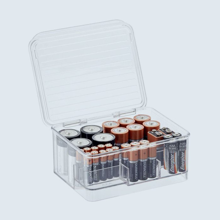 Plastic box holds various batteries neatly in separate compartments with its lid open, set against a plain background.