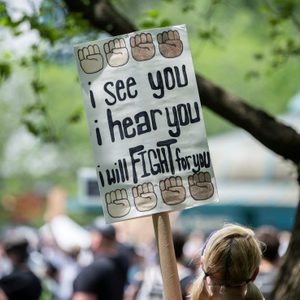 A protest sign displays the text, 
