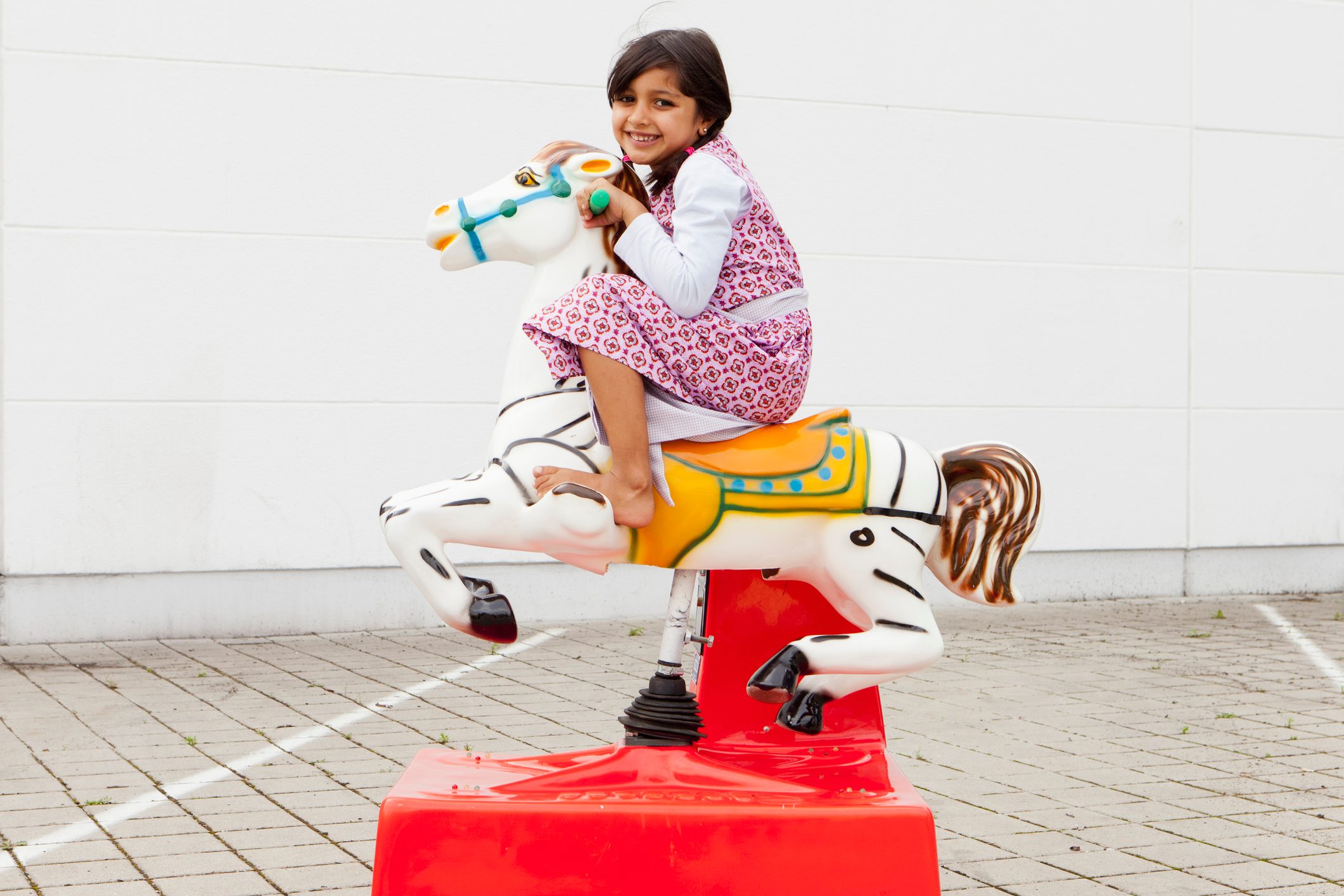 Girl riding mechanical horse outdoors
