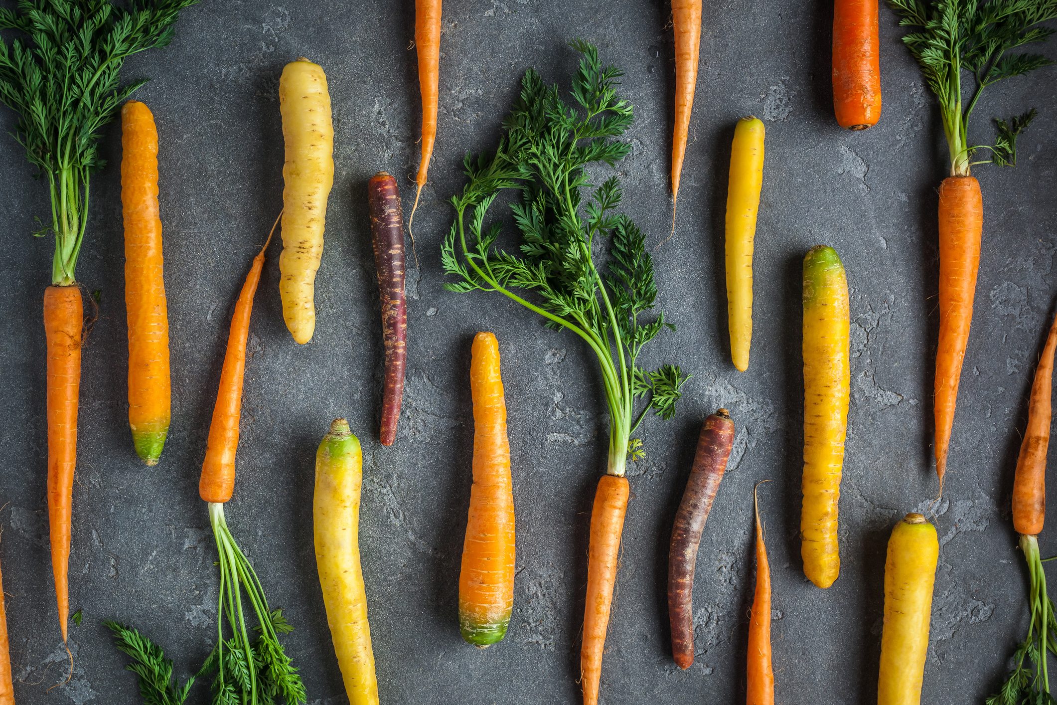 Fresh colorful carrots on dark background. Flat lay, top view