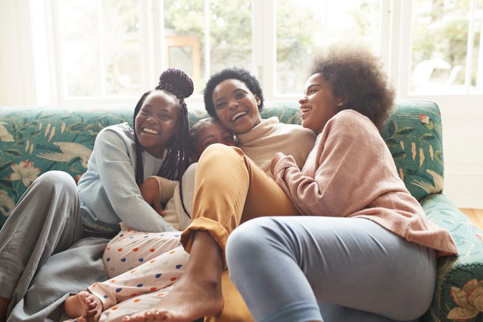 Portrait of happy woman embracing girls at home