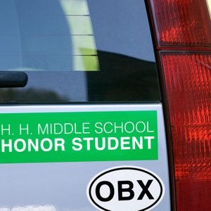 A car displays two stickers: green reads 