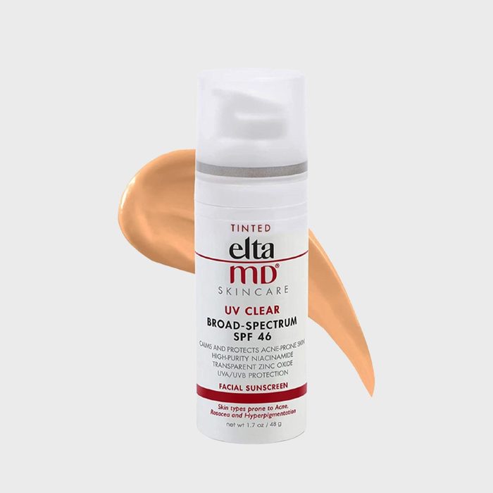 Sunscreen bottle stands with beige smear behind; labeled 