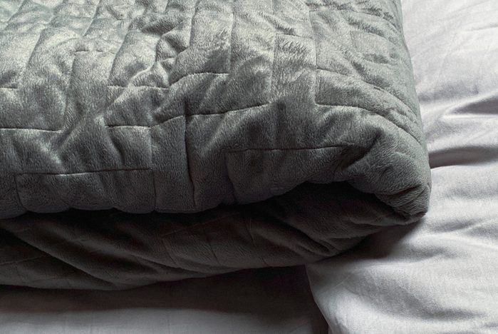 Still life of gray, weighted, blanket in bedroom