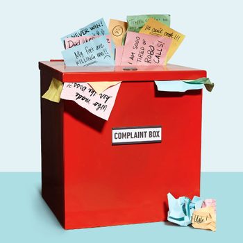 Red box labeled "COMPLAINT BOX," overflowing with colorful notes expressing various complaints, surrounded by crumpled notes on a light blue surface.