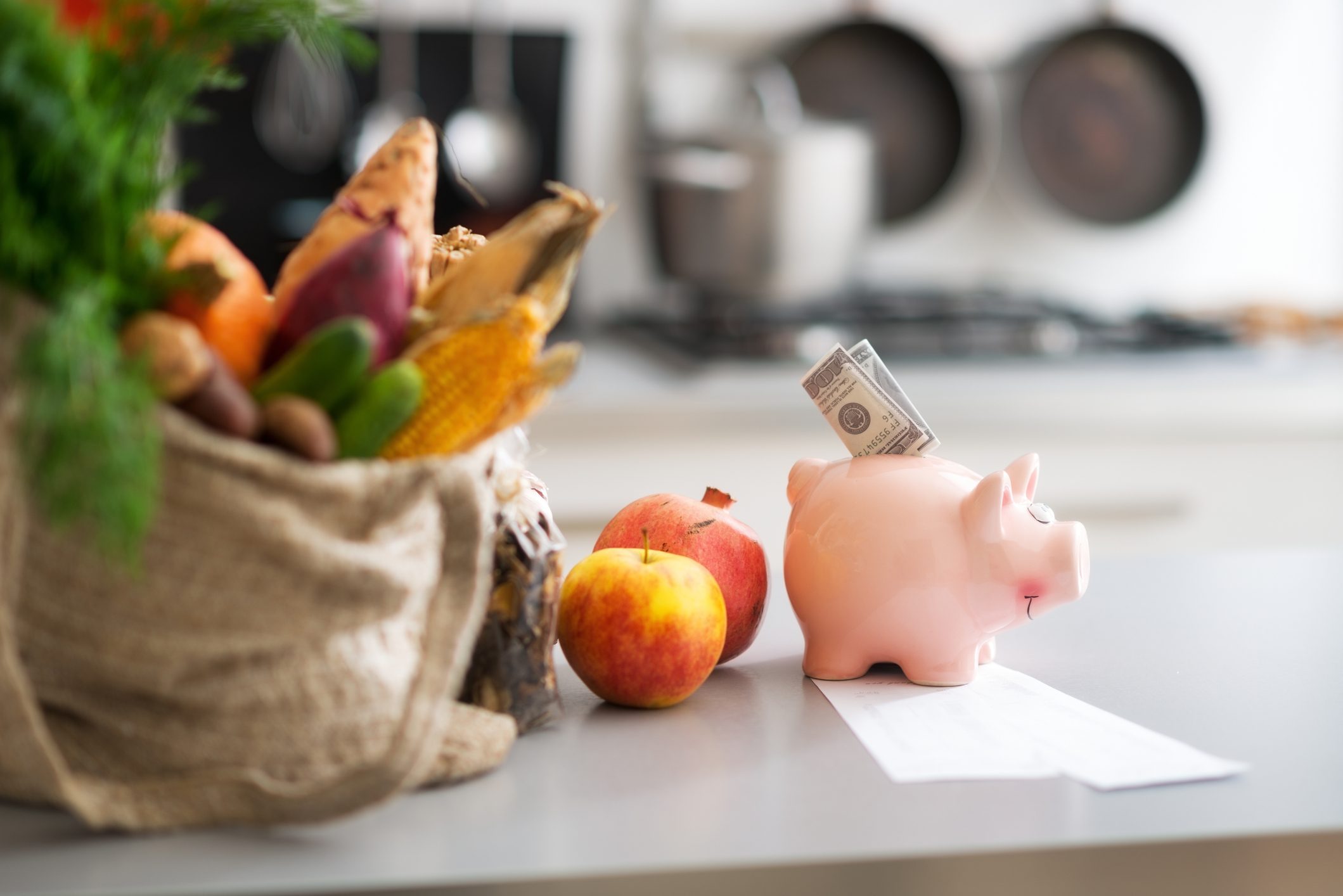 Money in piggy bank and purchases on table. Closeup