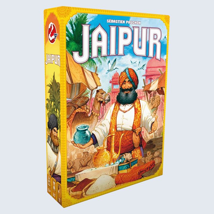 A colorful game box shows a merchant holding a jar, smiling, with a camel nearby in a bustling market scene. Text: 