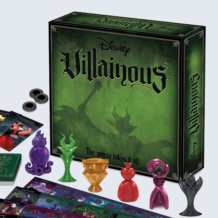 Box stands showcasing Disney's Villainous game; colorful character figures and cards surround it on a tabletop.