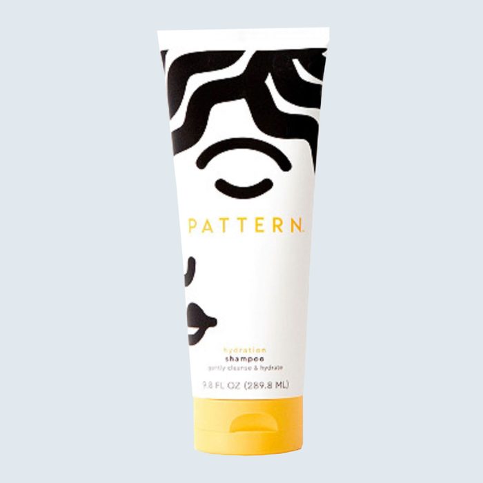 Shampoo bottle stands upright, displaying bold black patterns on a white background with yellow text 