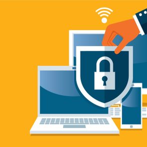 A hand places a lock shield over a laptop, tablet, and smartphone with a Wi-Fi symbol above, on a yellow background.