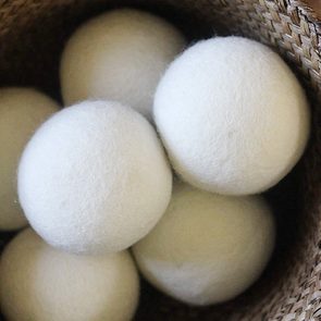 Wool dryer balls resting inside a woven basket, clustered together.